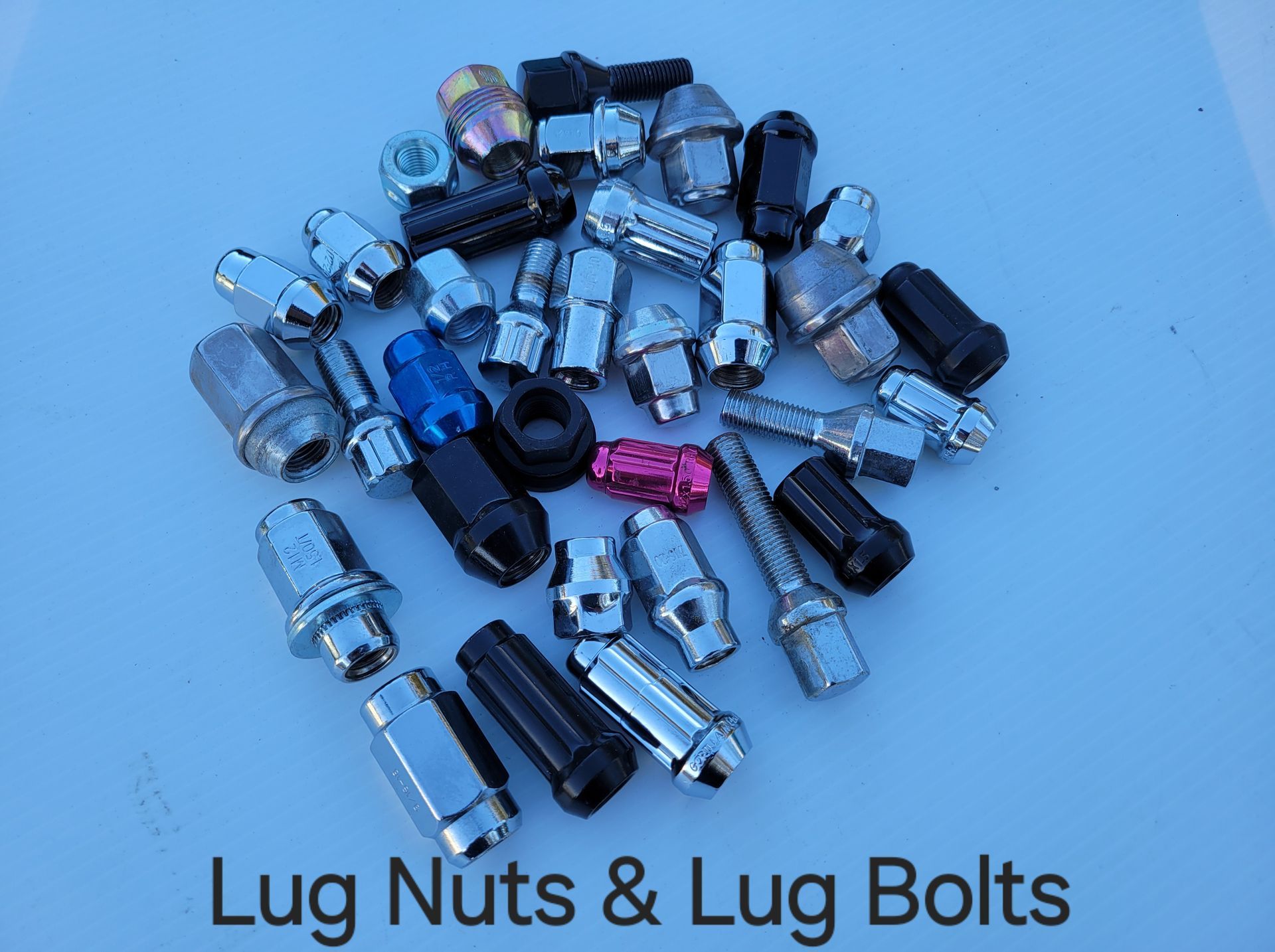 Scattered assortment of black, silver, and red lug nuts. Scattered assortment of black, silver, and red lug nuts.