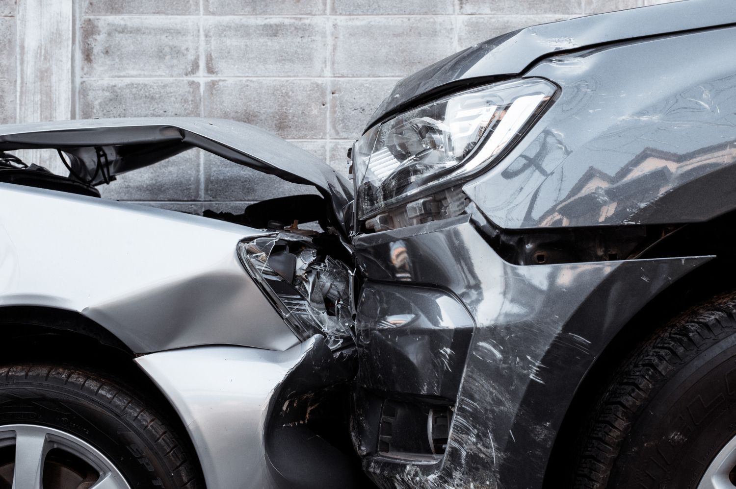 Two cars involved in a front-end collision, with severe damage to the black car’s hood and bumper.