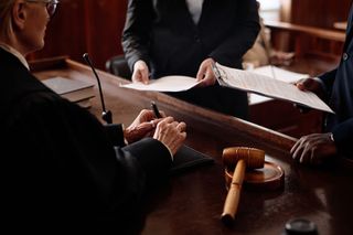 Courtroom scene with a judge, lawyers exchanging papers, and a gavel on the bench