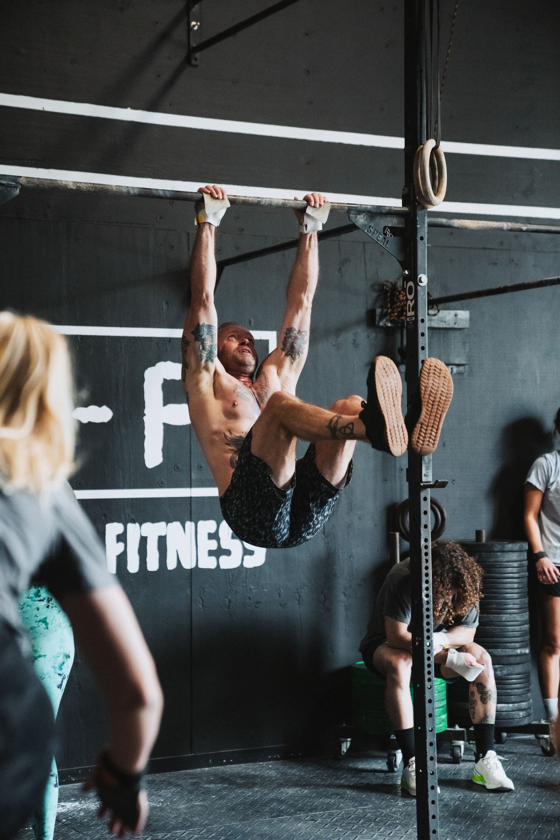 Man doing hanging leg raises in a gym.  Black wall with 
