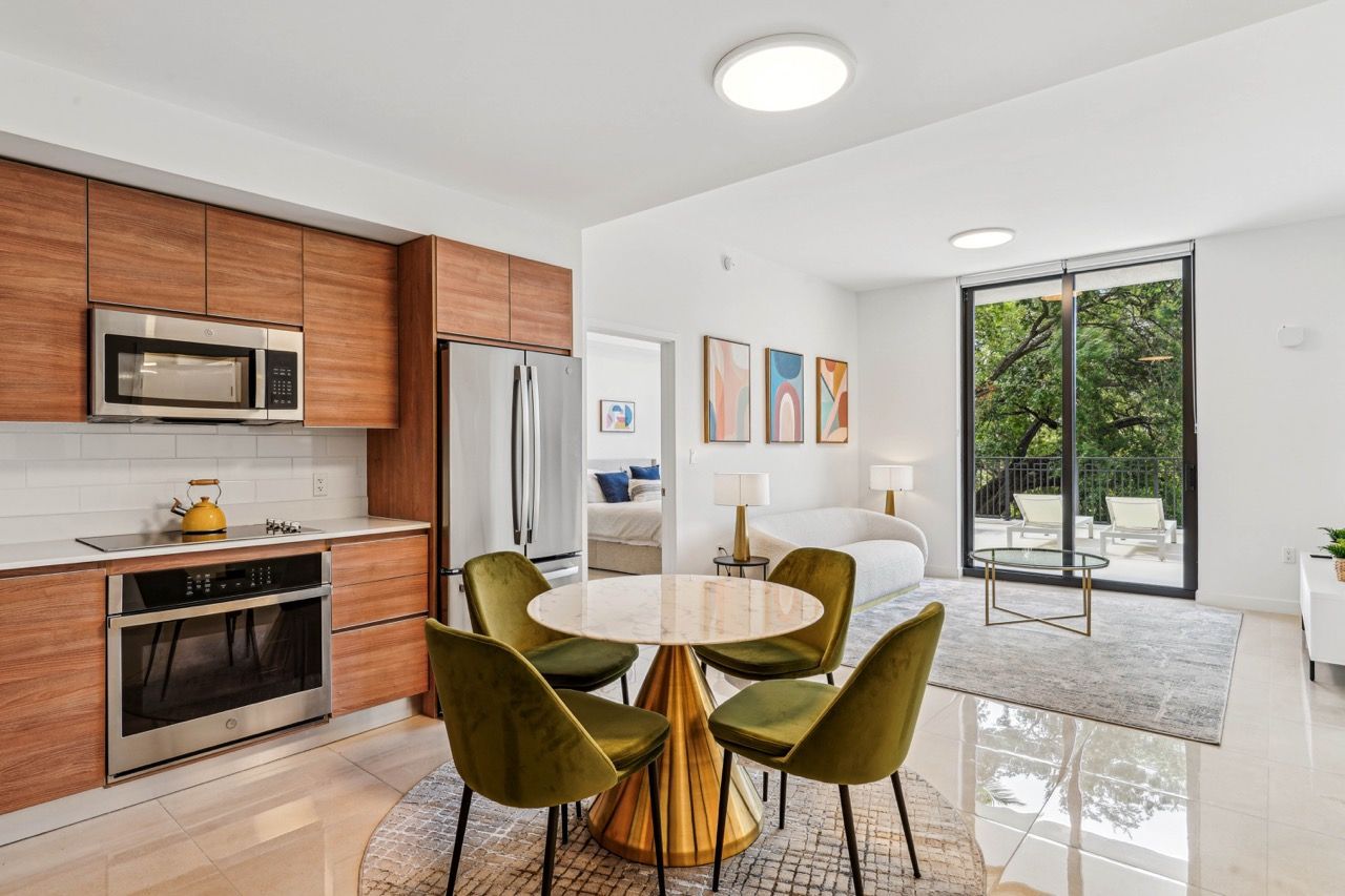 Open-concept kitchen and living area with a round marble dining table and sliding door to balcony.