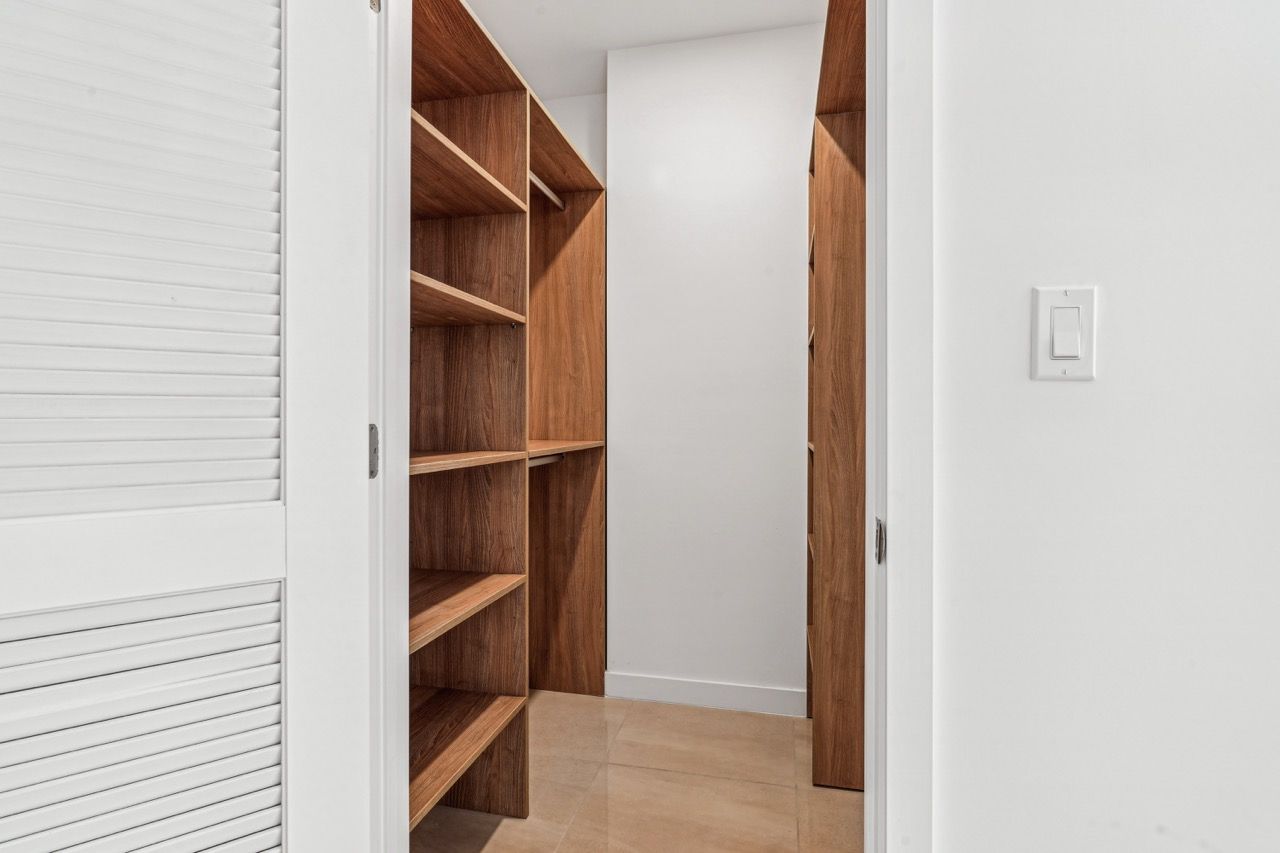 Walk-in closet with tall wooden shelves and rod storage along white walls.
