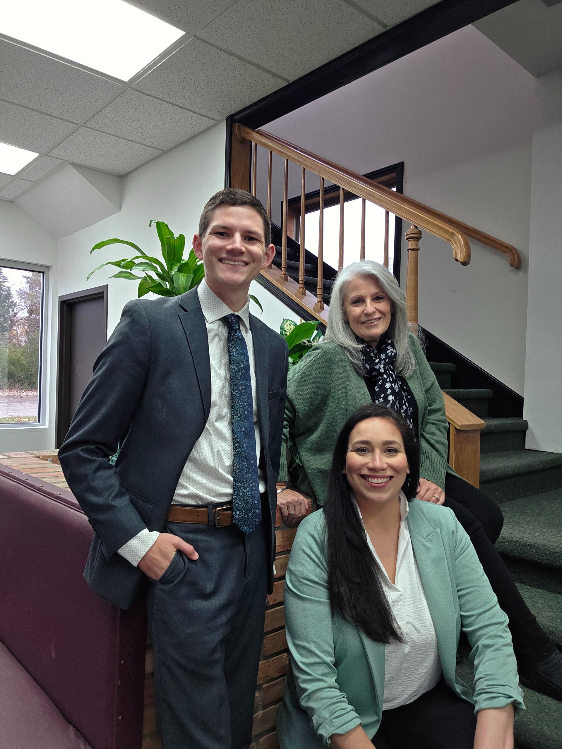 A man and two women are posing for a picture in front of a brick wall.