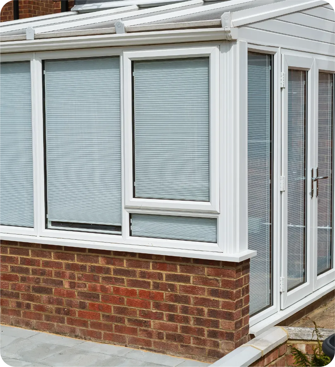 A white conservatory with blinds on the windows and doors.
