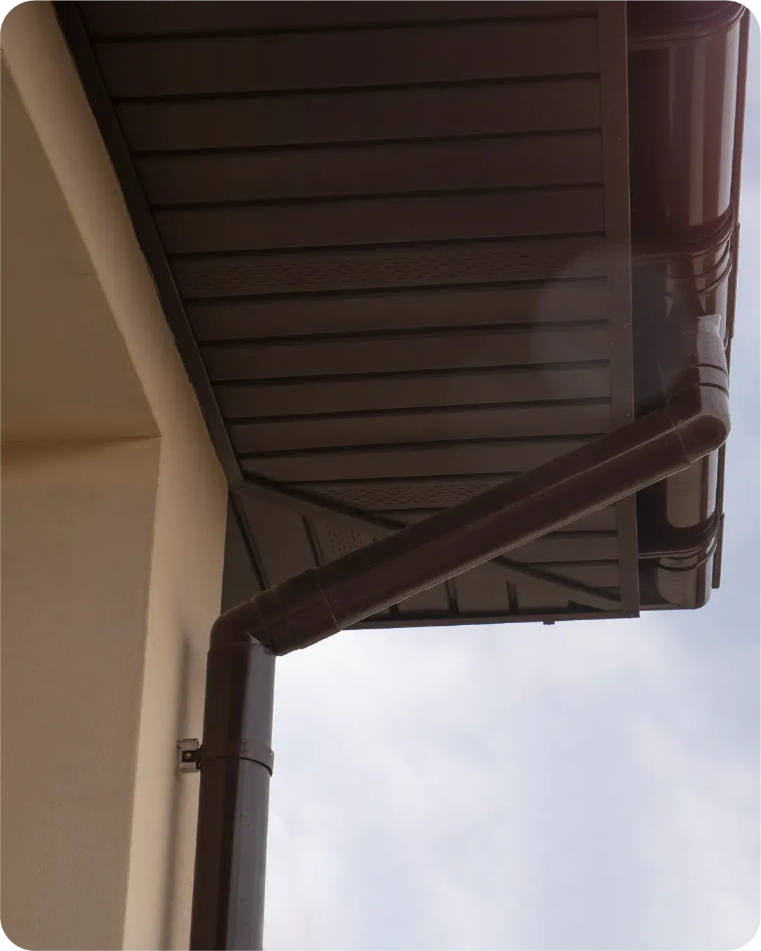 A brown gutter on the side of a building
