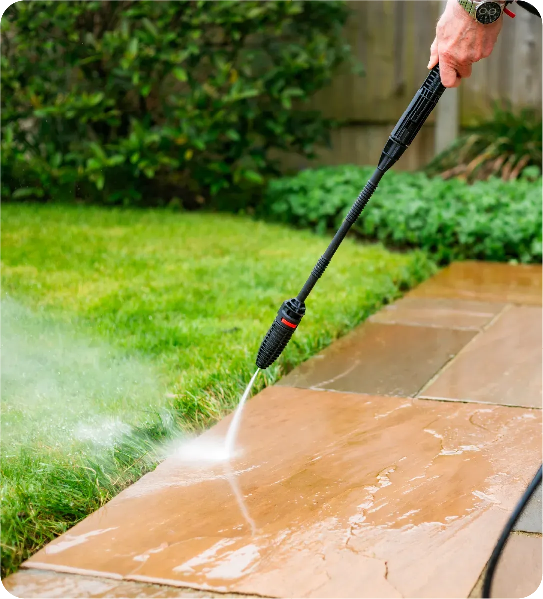 A person is using a high pressure washer to clean a sidewalk.
