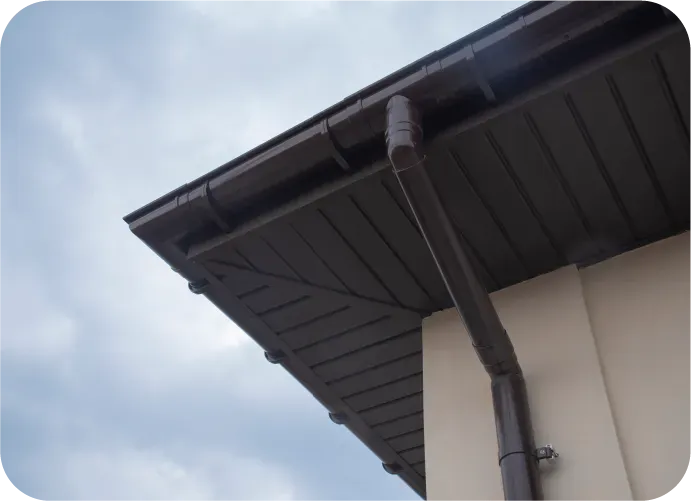 A house with a brown gutter and a blue sky in the background