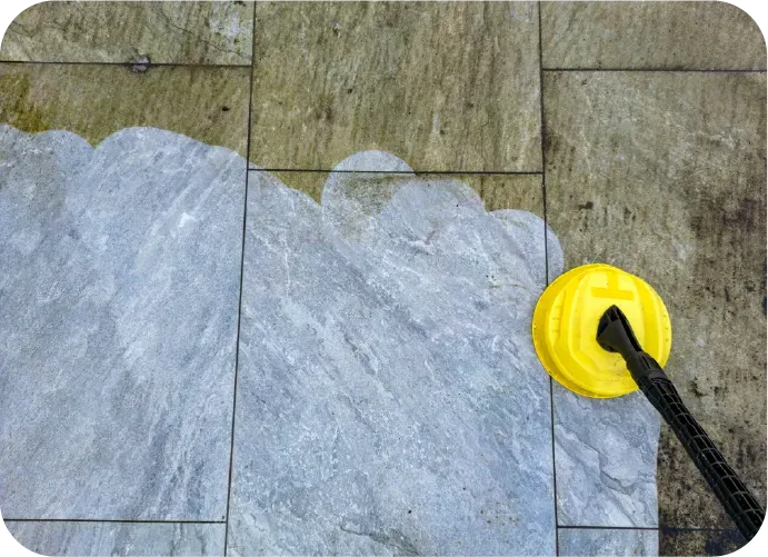 A person is cleaning a tile floor with a yellow brush
