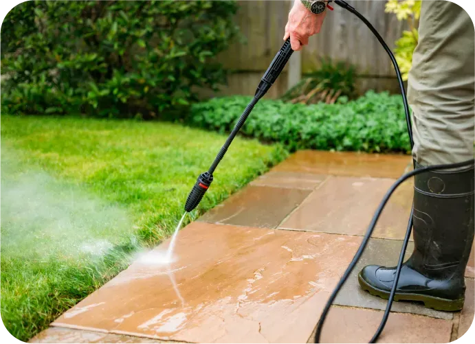 A person is using a high pressure washer to clean a sidewalk.