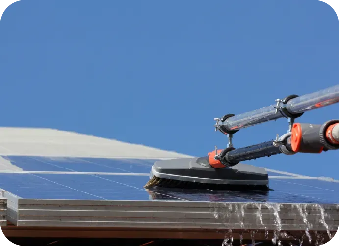 A person is cleaning a solar panel with a brush.