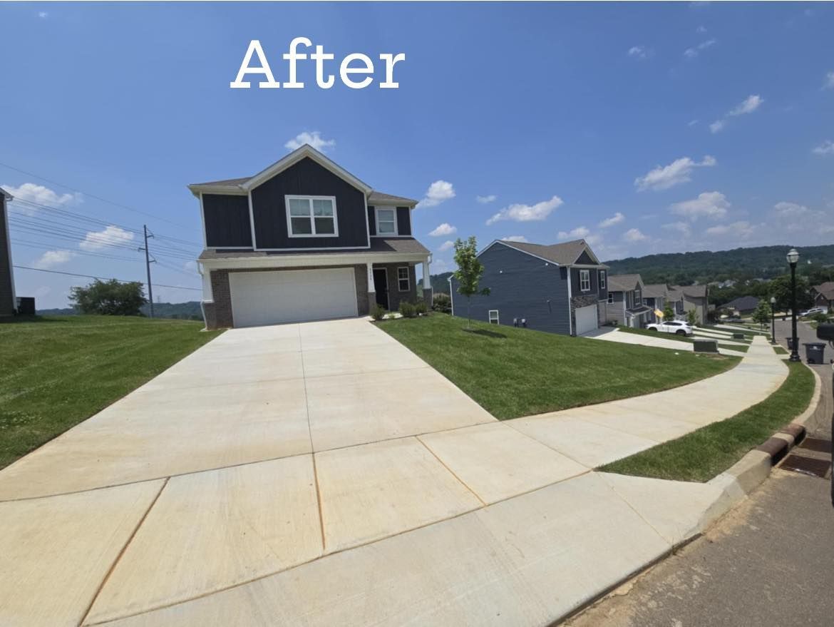 Two-story house with blue siding, white garage door, and concrete driveway on a sunny day.