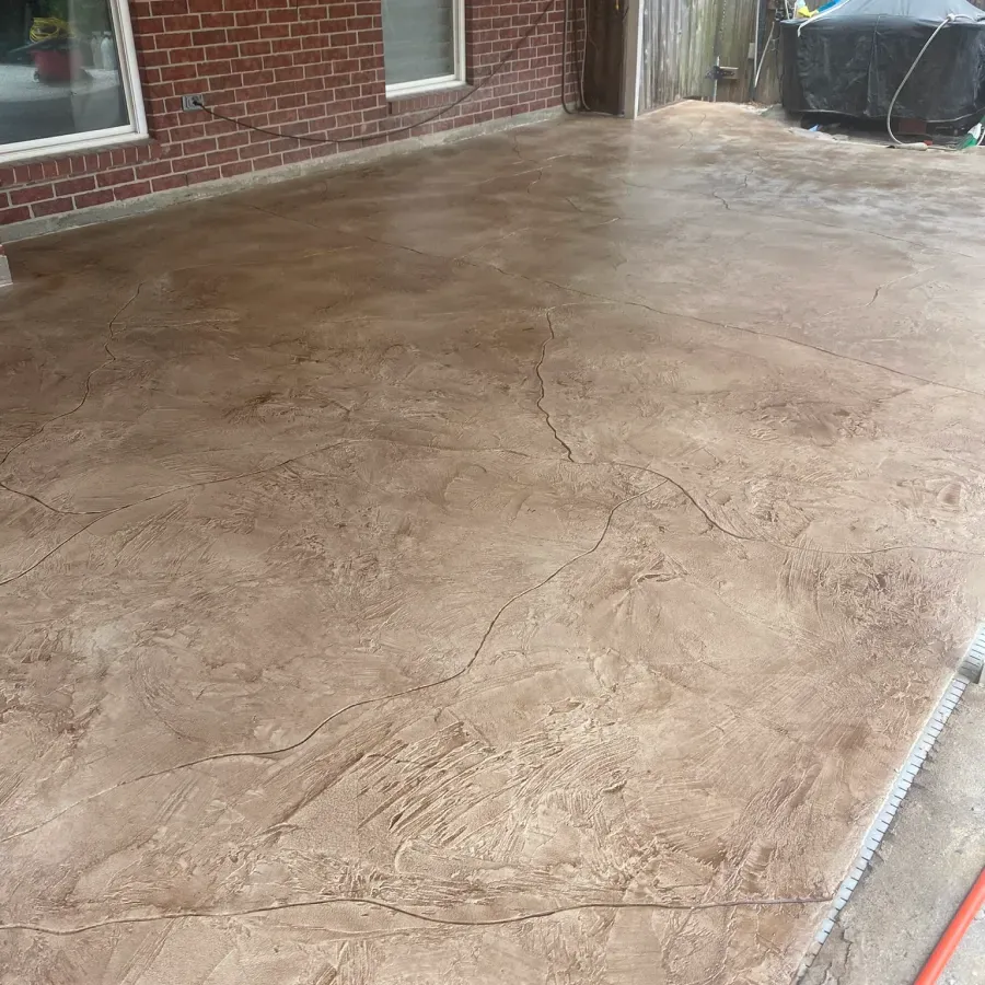 A patio with a brick wall and a concrete floor.