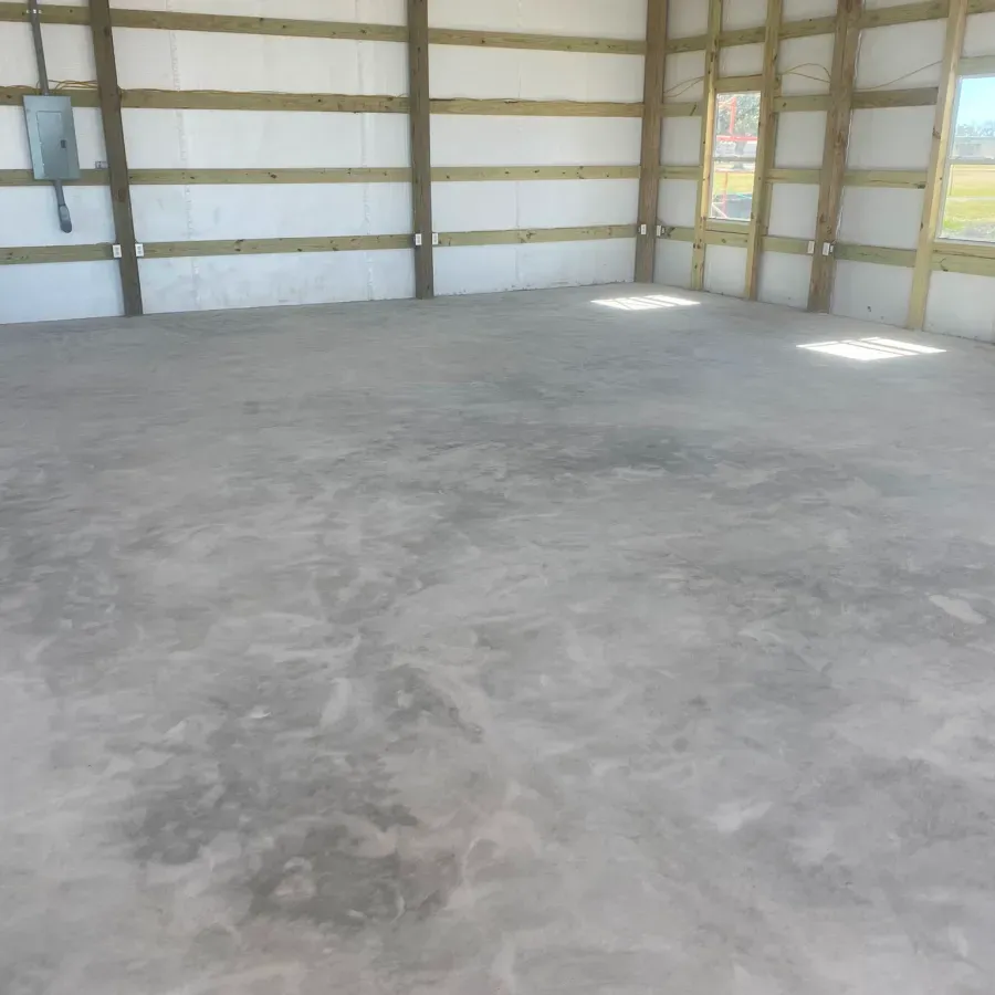 A large empty room with a concrete floor and wooden walls.