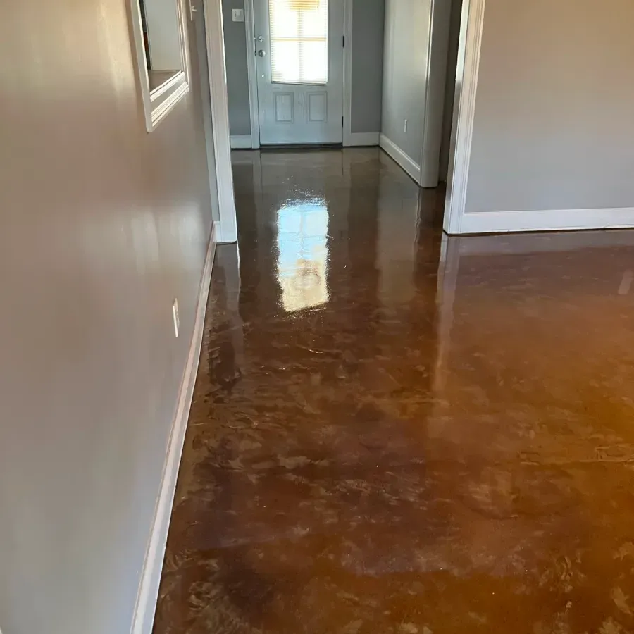 A hallway with a stained concrete floor and a door.