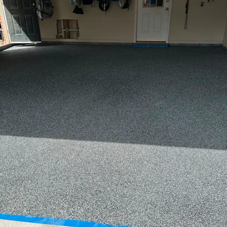 A garage with a gray floor and a blue stripe on the floor.