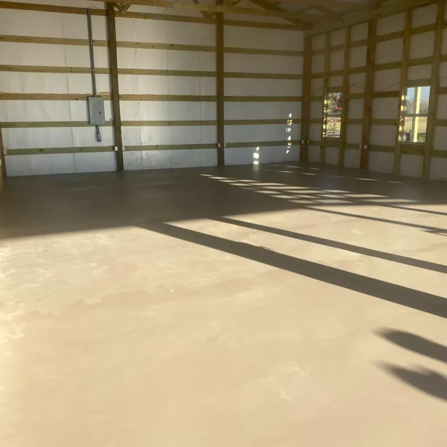 A large empty room with a concrete floor and wooden walls