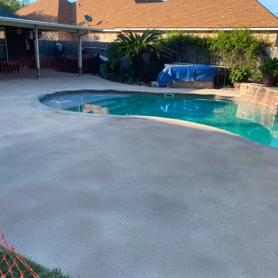 There is a large swimming pool in the backyard of a house.