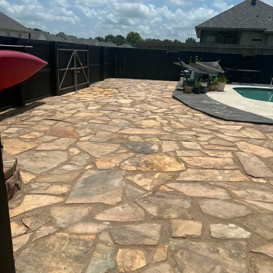 A stone patio with a pool in the background