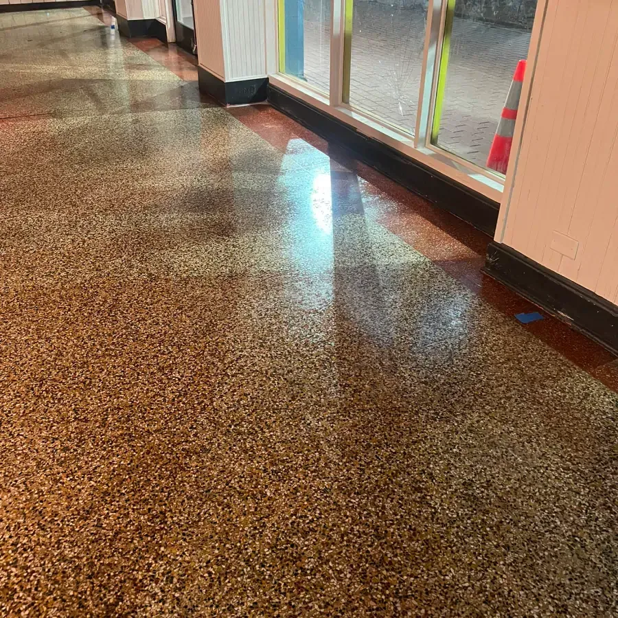 A shiny concrete floor in a hallway next to a window.