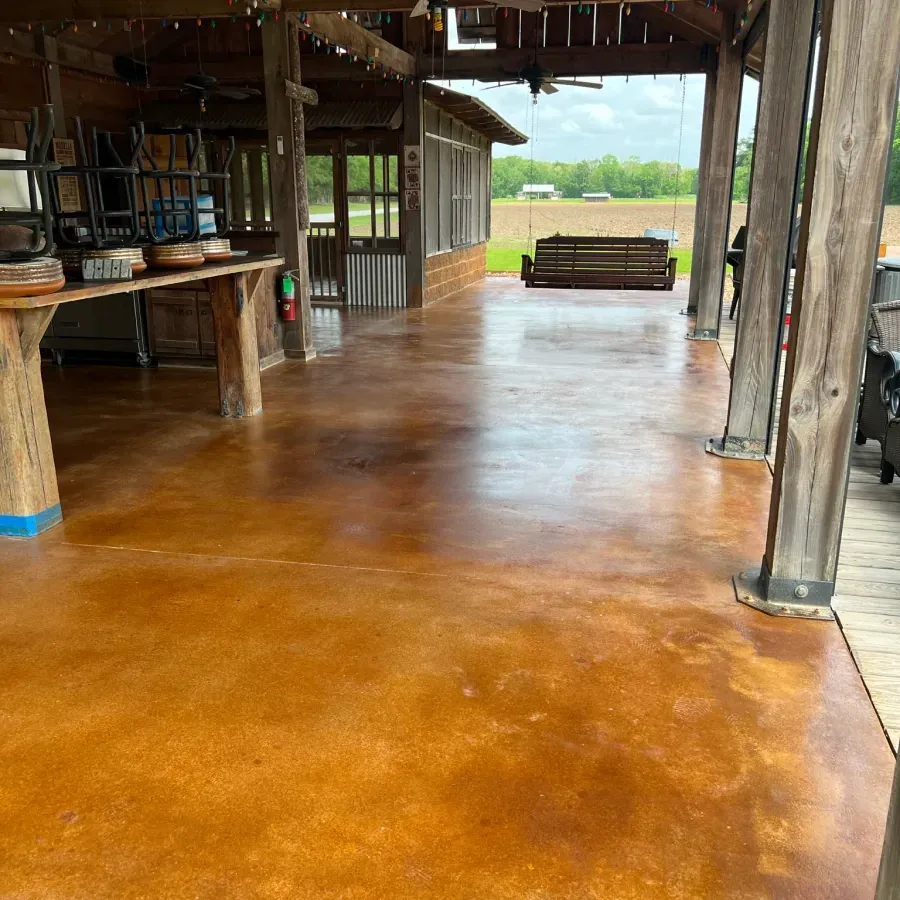 A covered patio with a stained concrete floor and wooden pillars.