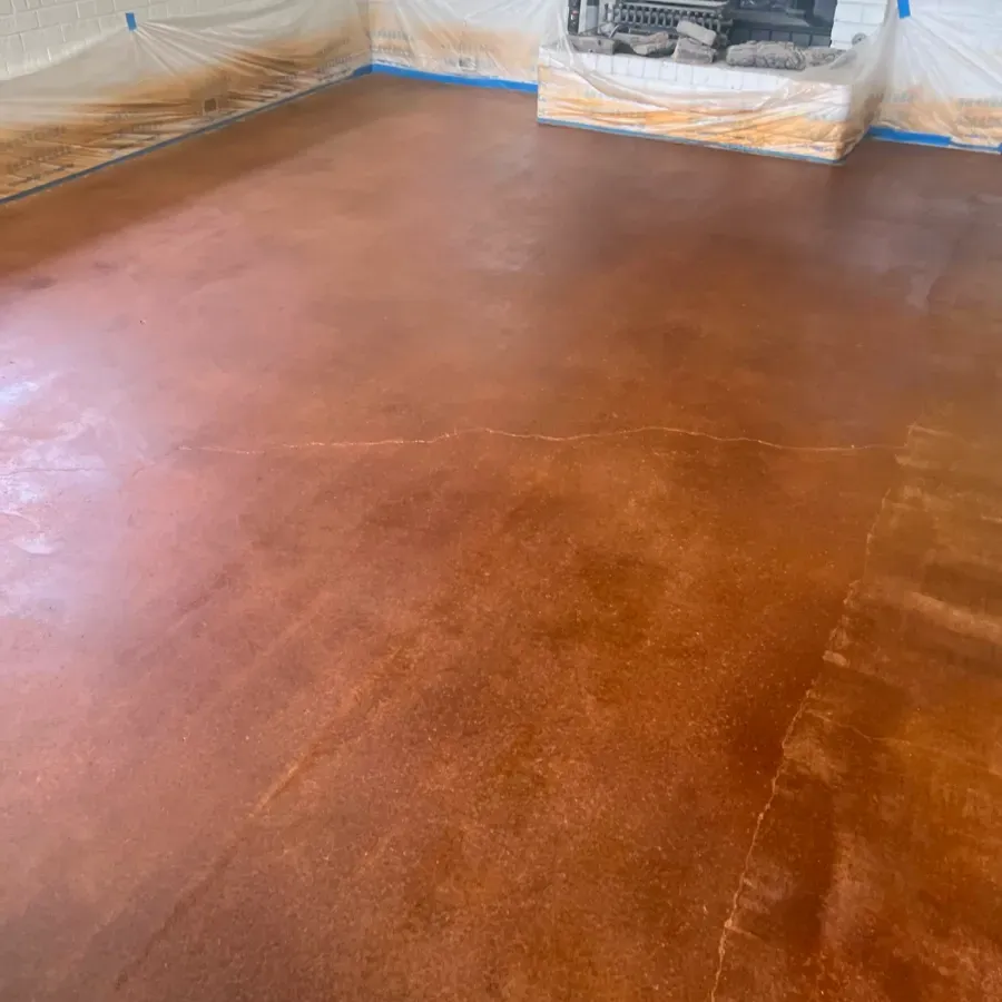 A living room with a stained concrete floor and a fireplace.