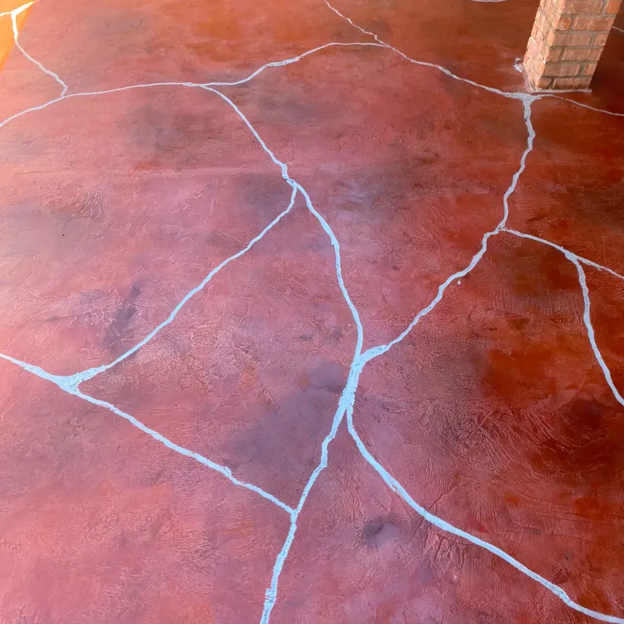 A close up of a red concrete floor with white cracks