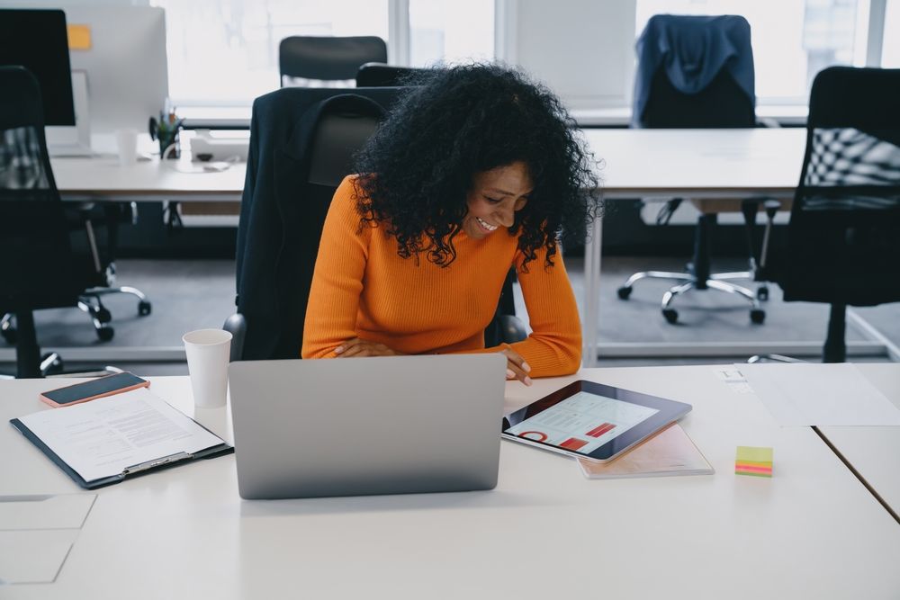 A woman is sitting at a desk using a laptop computer.