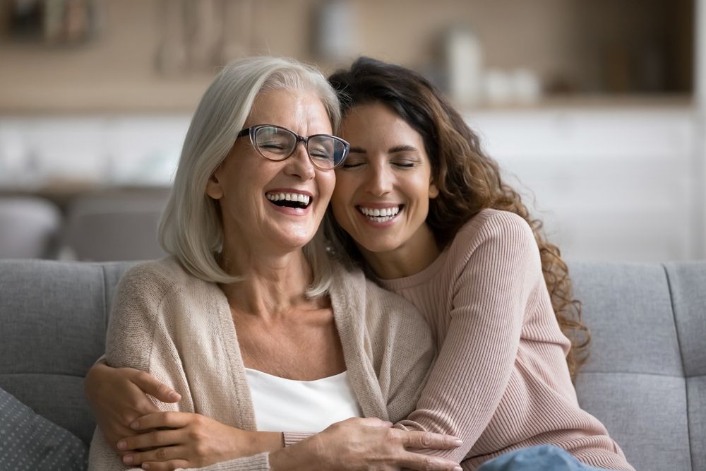 A young woman is hugging an older woman on a couch.