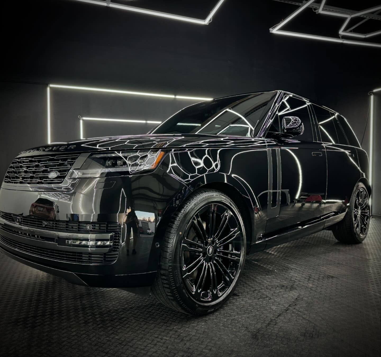 A black car is parked in a dark room