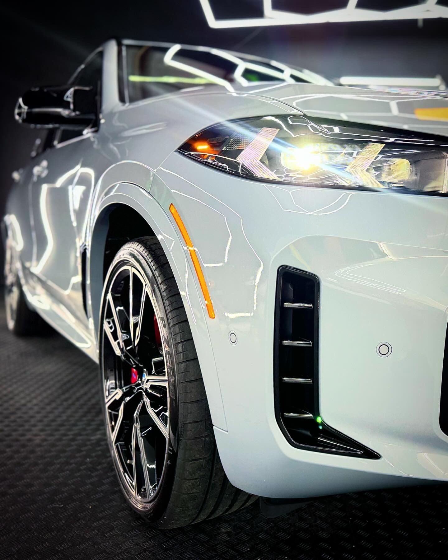 A white bmw x5 is parked in a dark room.