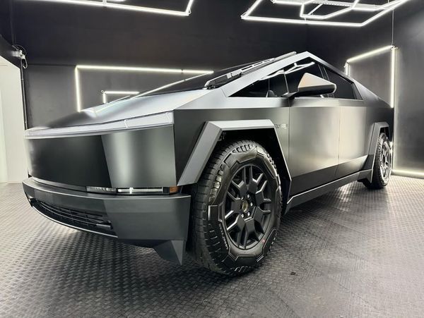 A grey tesla cybertruck is parked in a garage.