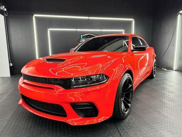 A red dodge charger is parked in a garage.