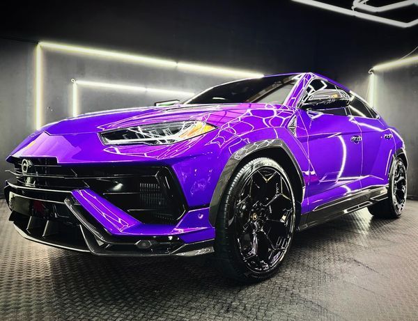 A purple lamborghini urus is parked in a garage.