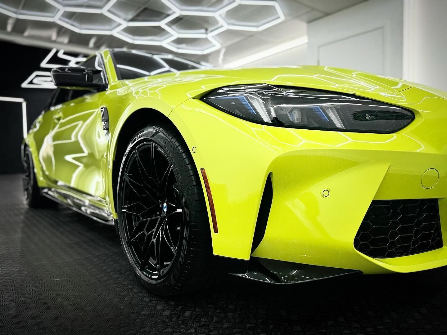 A yellow bmw m4 is parked in a garage.