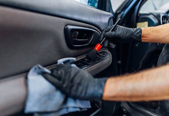 A man is cleaning the interior of a car with a brush.