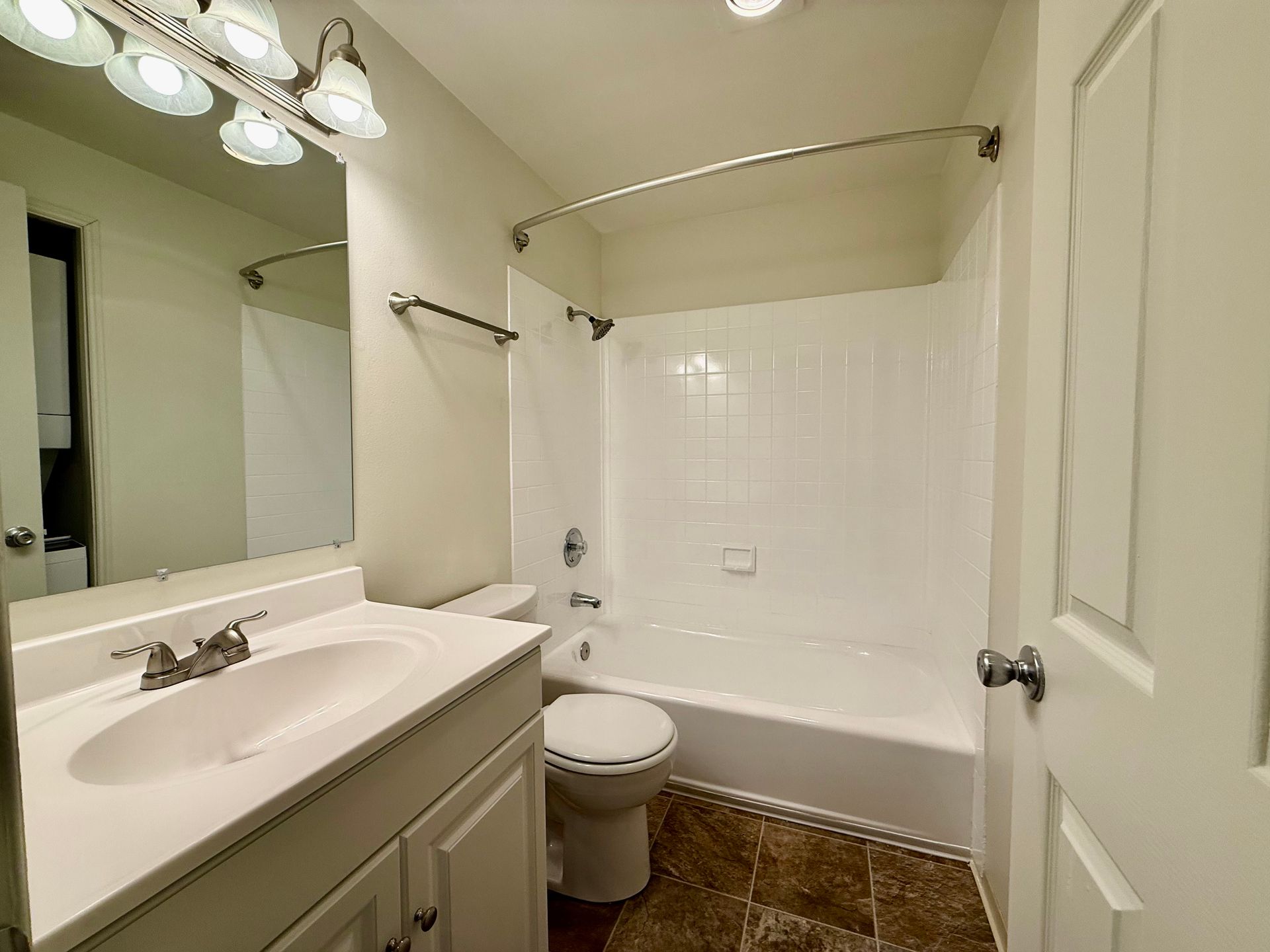 An empty bedroom with white walls and white closet doors.