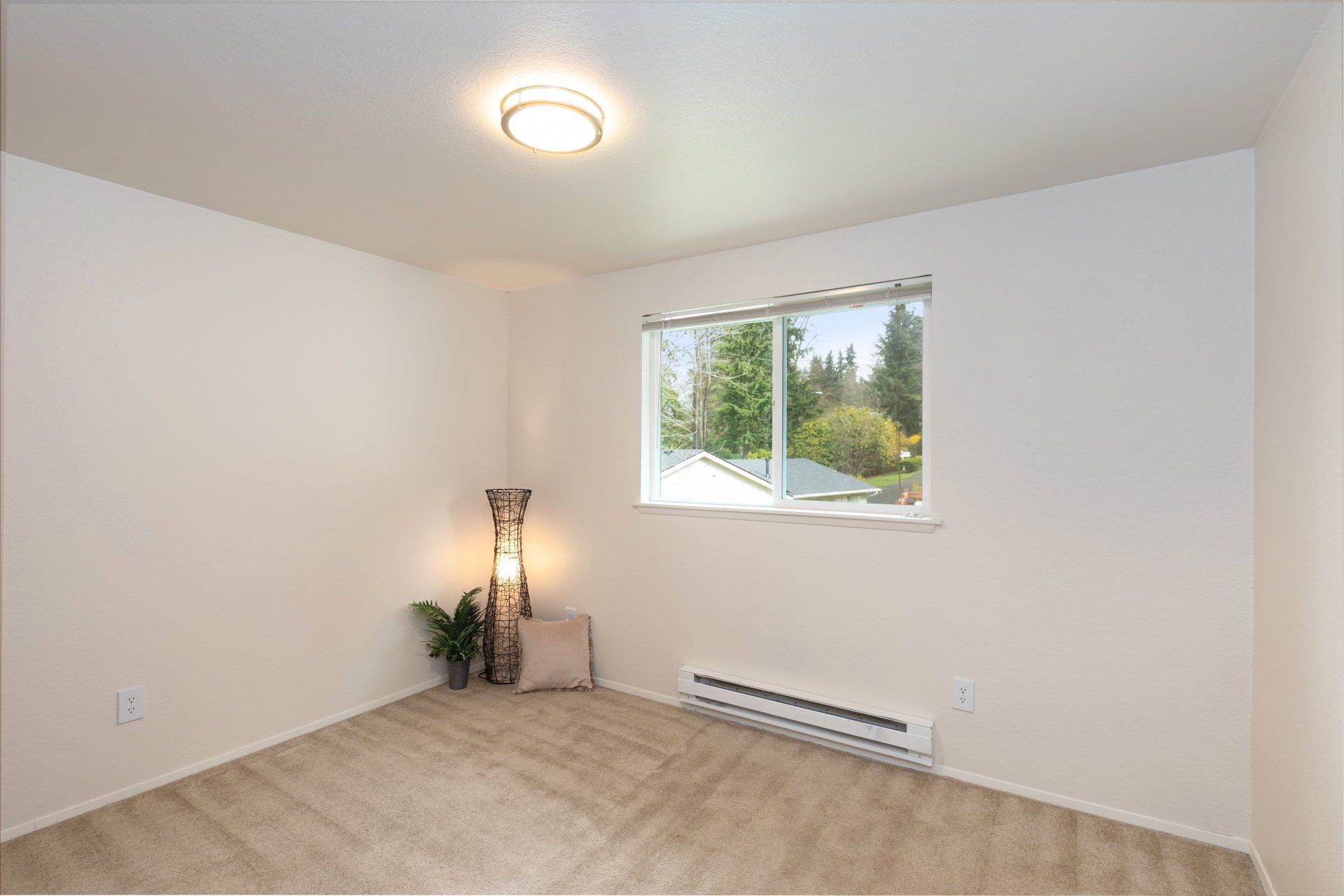 An empty bedroom with a window and a lamp.