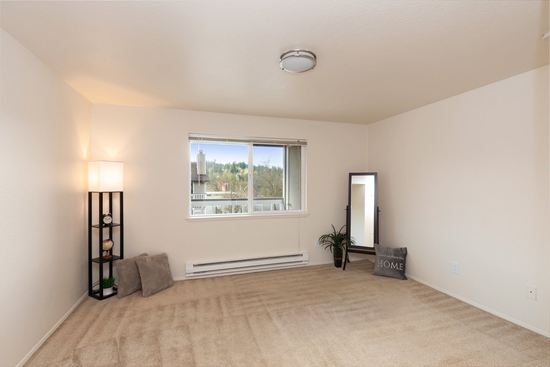 An empty living room with a large window and a mirror.