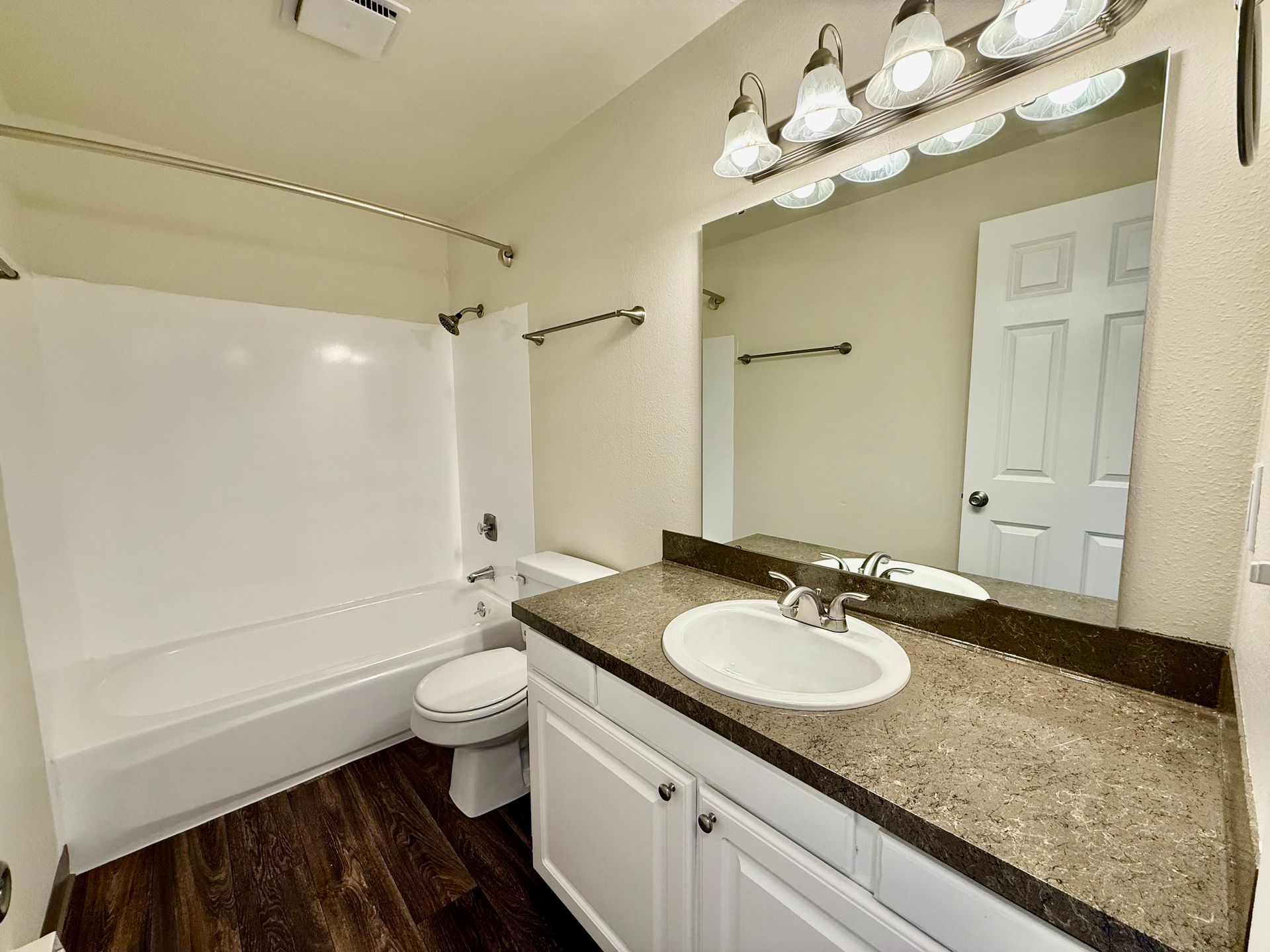 A bathroom with a sink , toilet , bathtub and mirror.