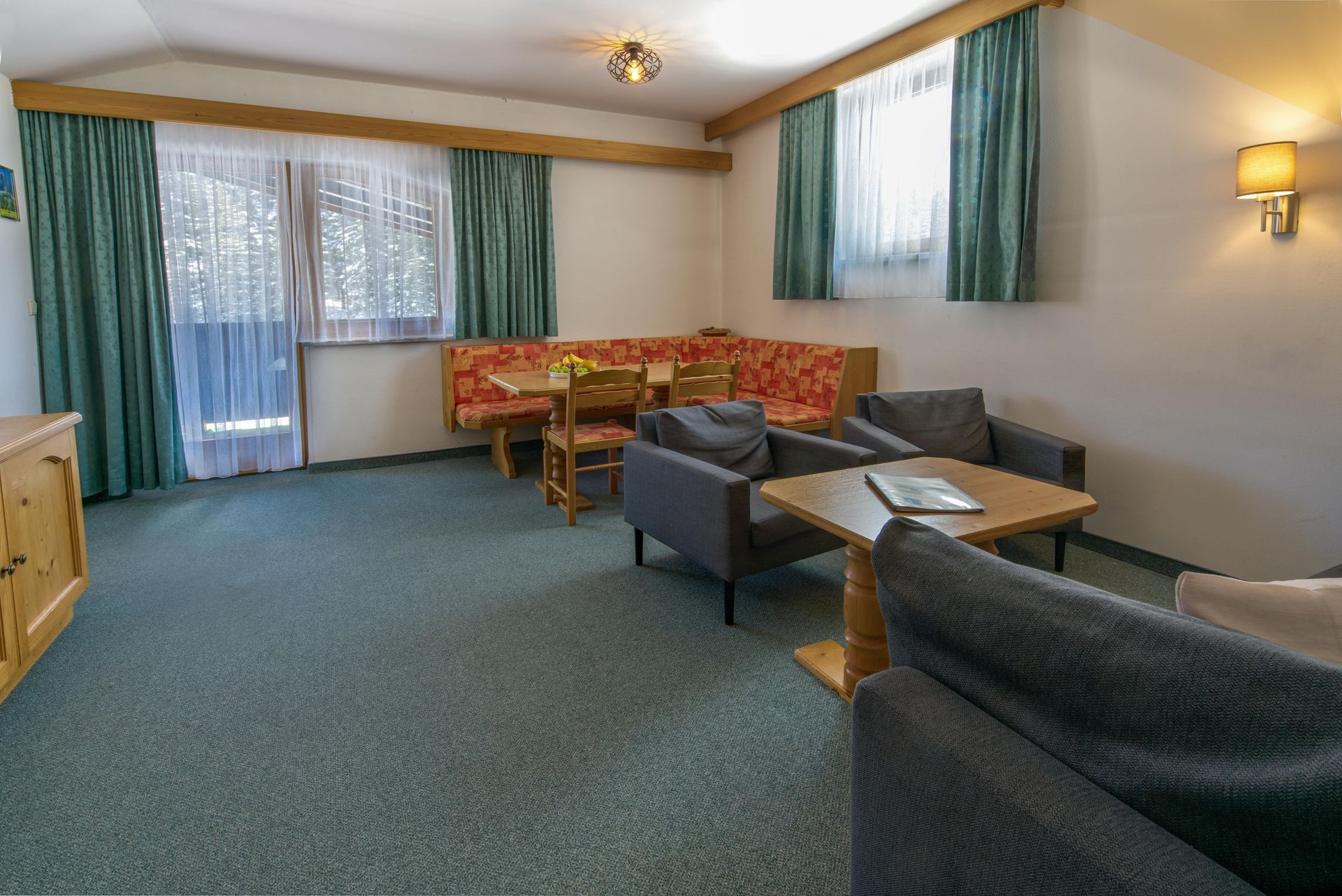 Een woonkamer met een bank, stoelen, tafel en gordijnen.