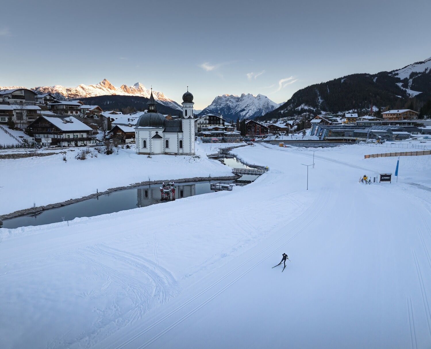 Eine Luftaufnahme einer verschneiten Landschaft mit einer Kirche im Hintergrund