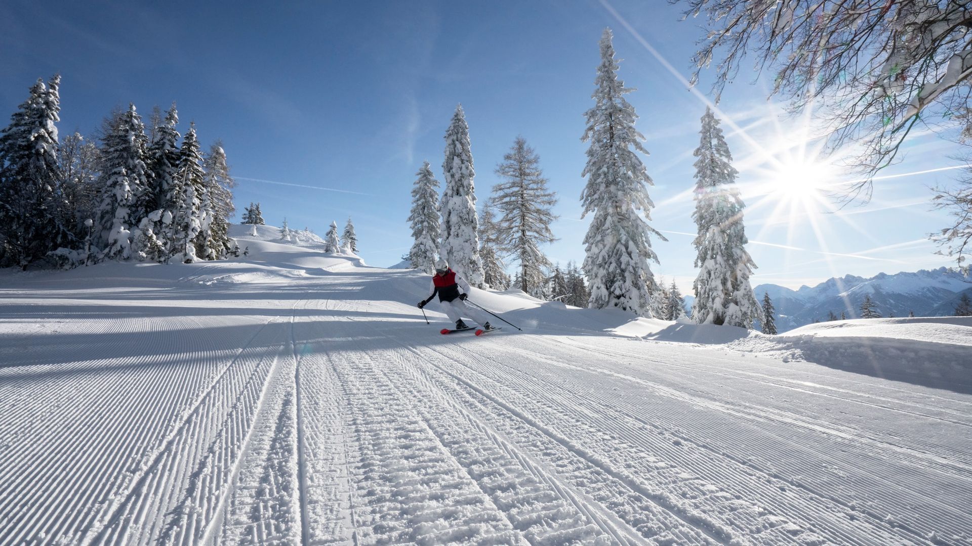 Eine Person fährt mit Skiern einen schneebedeckten Hang hinunter.