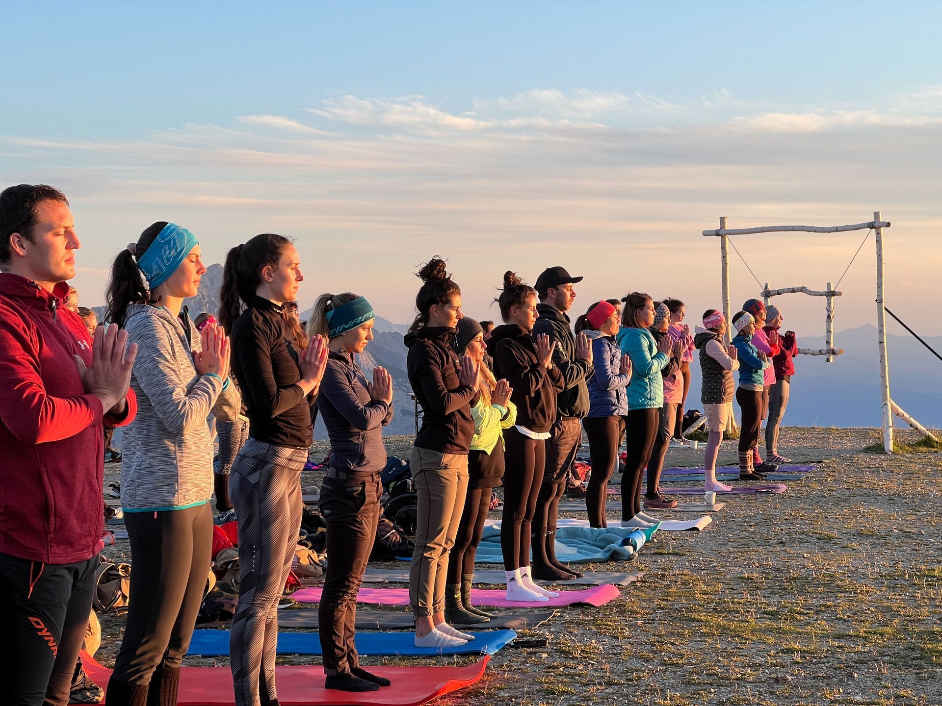 Eine Gruppe von Menschen steht in einer Reihe auf Yogamatten.