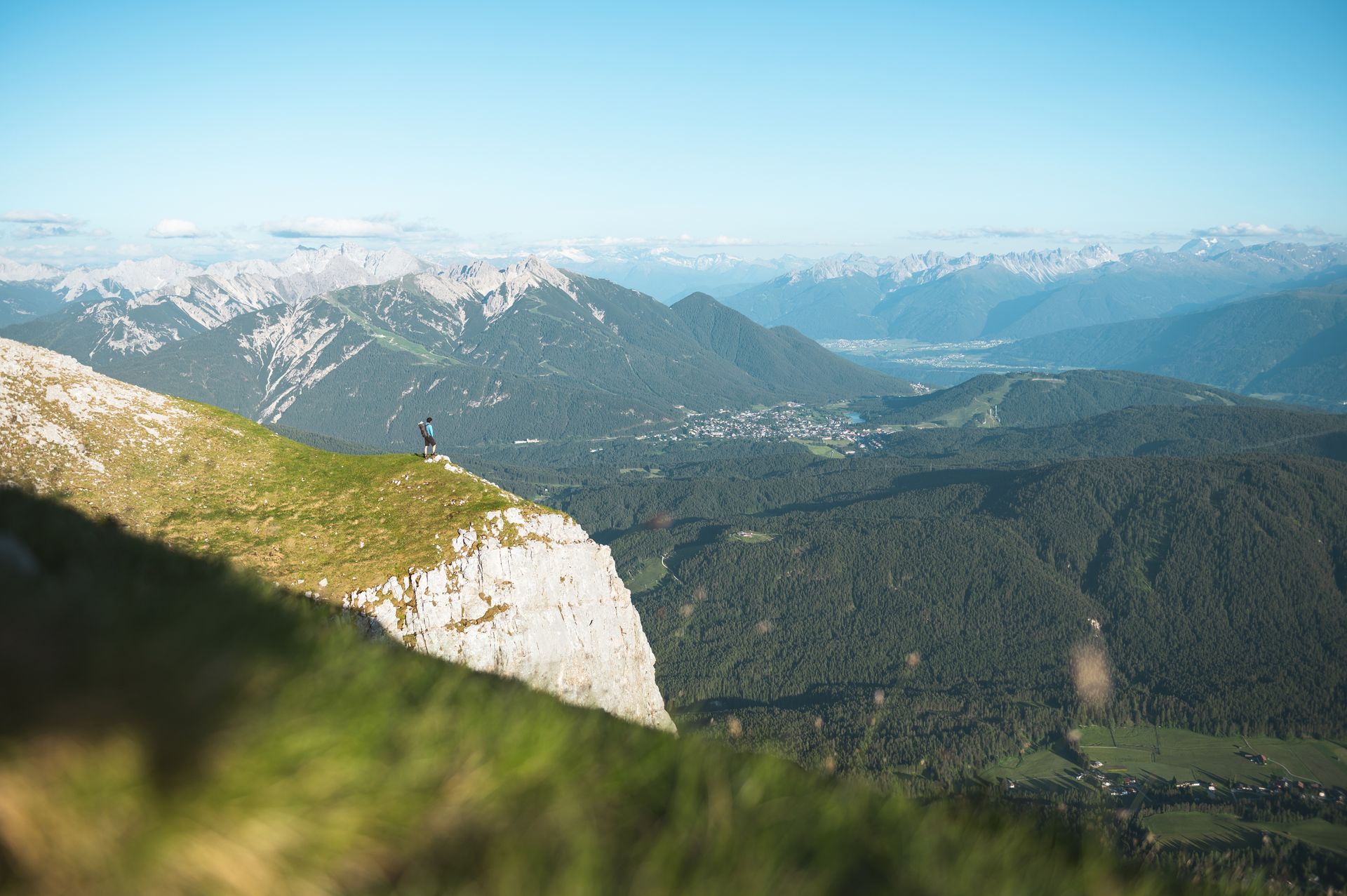 Eine Person steht am Rand eines Berges und blickt über ein Tal.