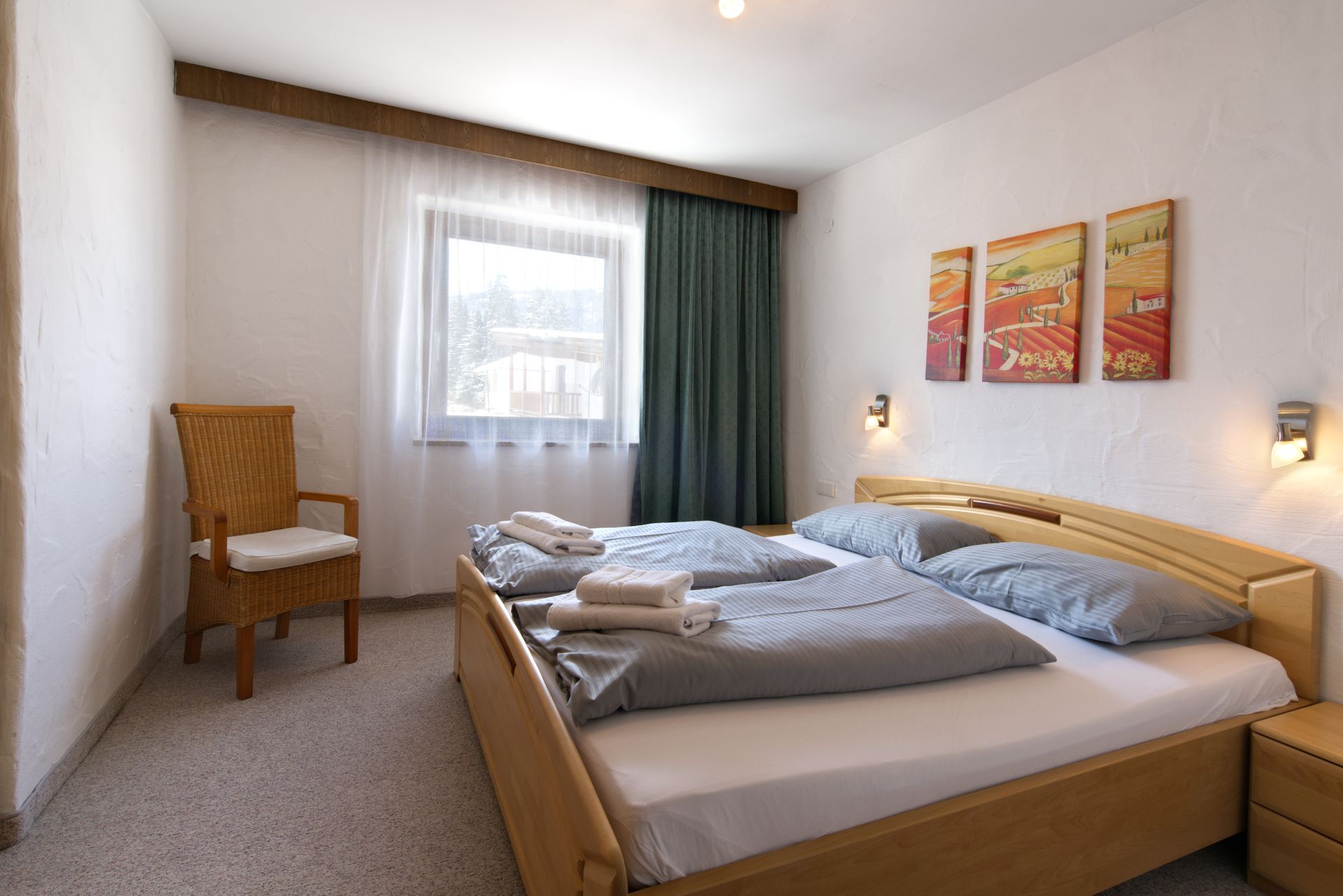 A bedroom with two beds , a chair and a window