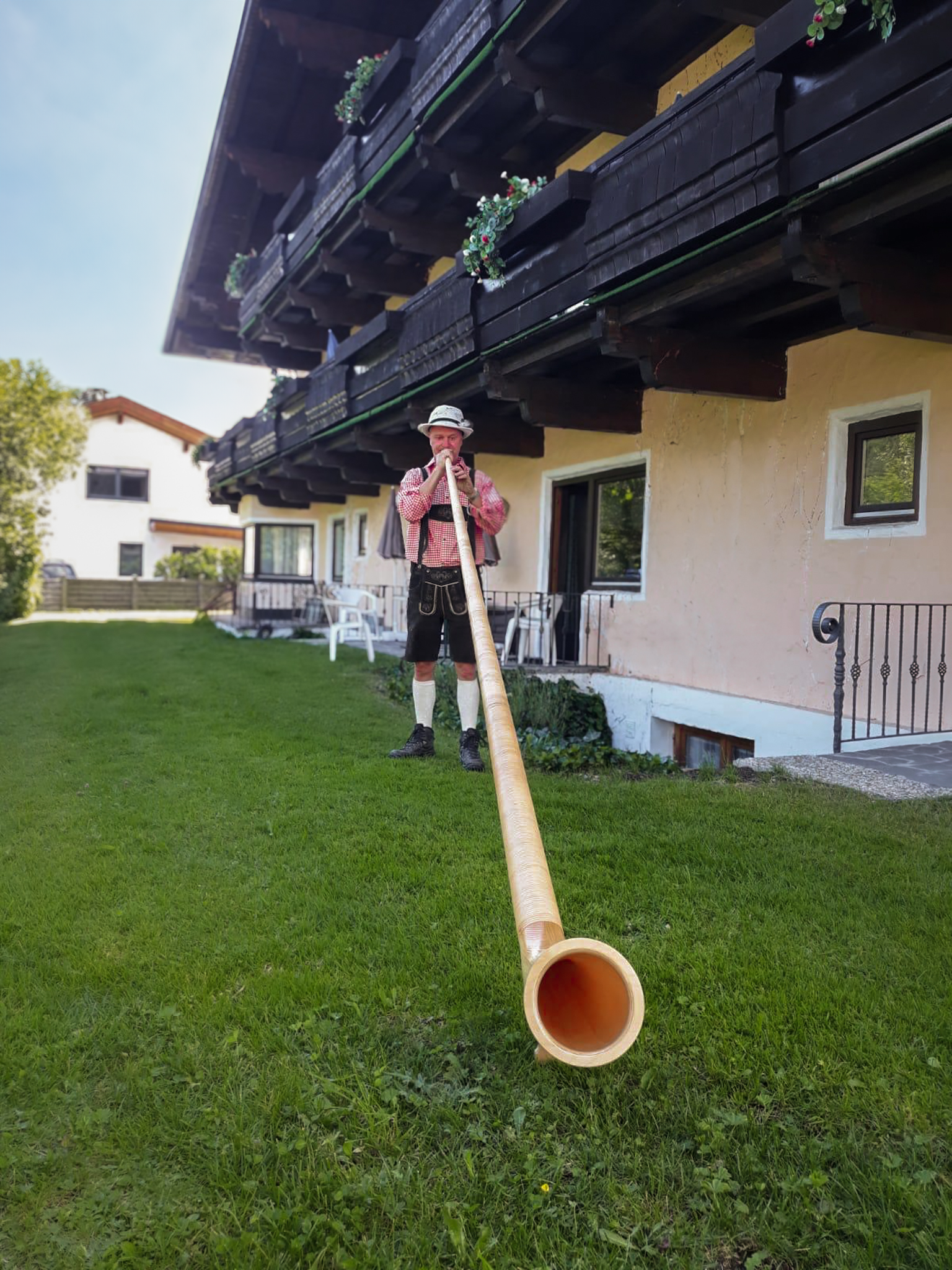 Ein Mann spielt vor einem Gebäude ein Horn.