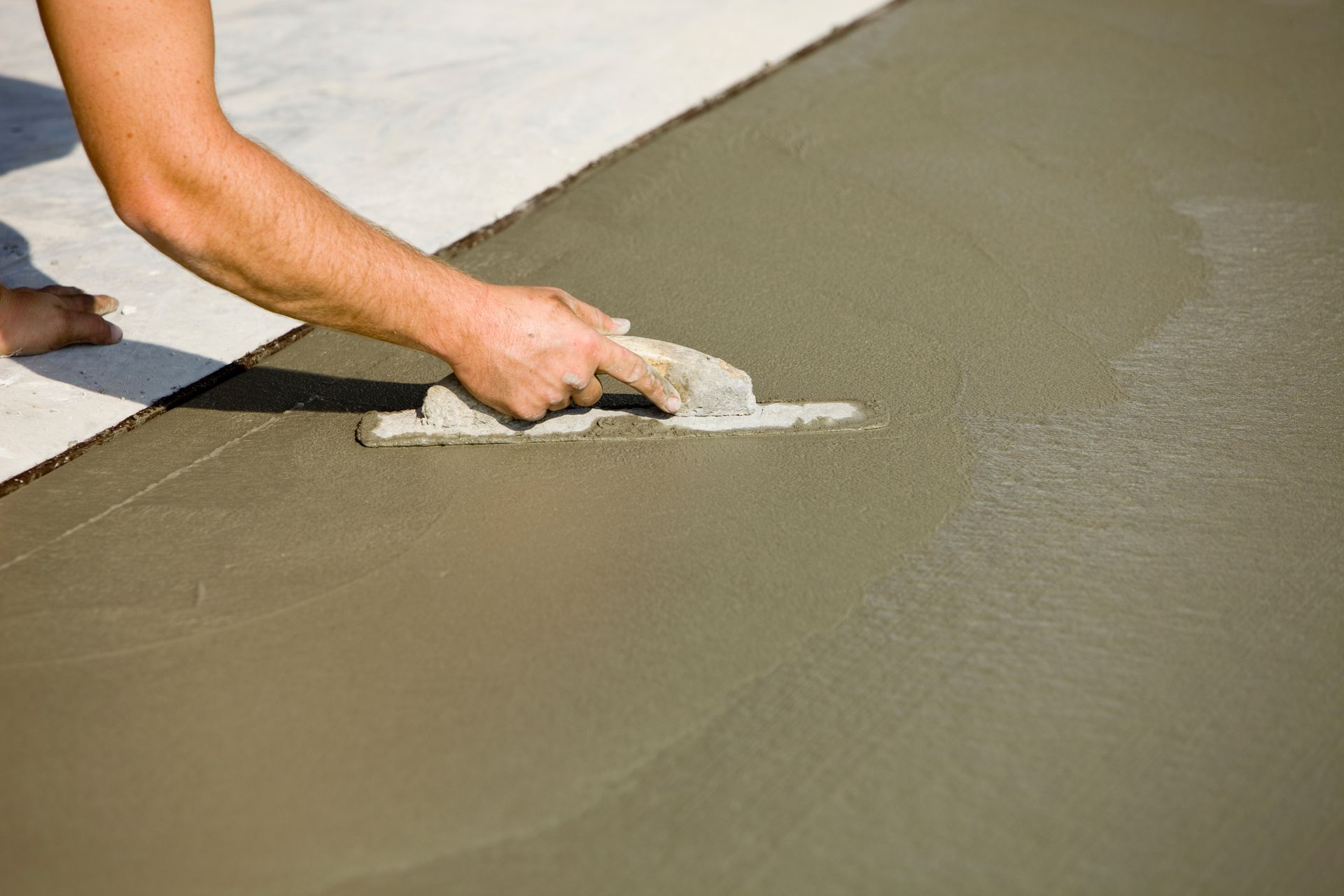 A worker using a cement mixer to prepare concrete for the installation of a new concrete driveway.