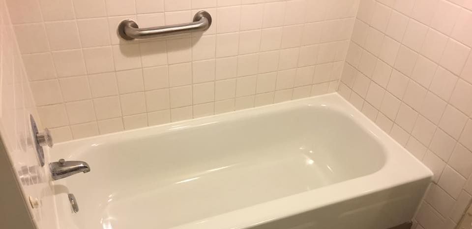There is a bathtub in the bathroom next to a toilet.