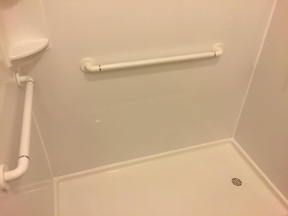 A shower stall with a white railing and a towel rack.