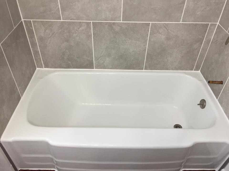 A white bathtub is sitting in a bathroom next to a tiled wall.